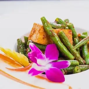 Green beans, tofu/paneer, reddish sauce, vegetable slices, and orchid garnish.