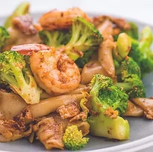 Colorful stir-fry with shrimp, broccoli, and noodles on a plate.