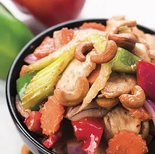 Colorful cashew chicken stir-fry with vegetables served in a dark bowl.