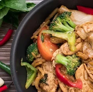 Colorful chicken stir-fry with broccoli, peppers, and tomato in a pan.