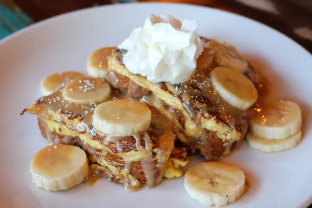 French toast or pancakes with syrup, bananas, powdered sugar, whipped cream.