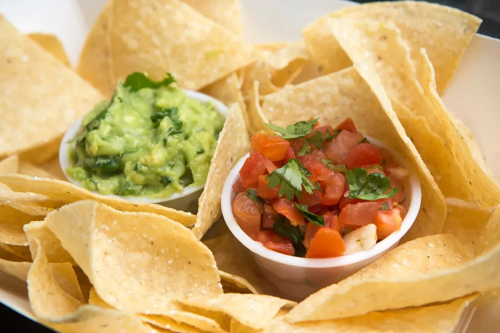 Golden tortilla chips with vibrant guacamole and fresh tomato salsa.