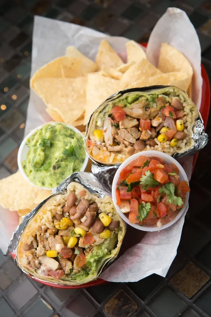 Top-down view: Two burritos, chips, guacamole, and pico de gallo.