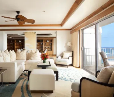 Luxurious living room with white sofa, blue rug, and ocean view.