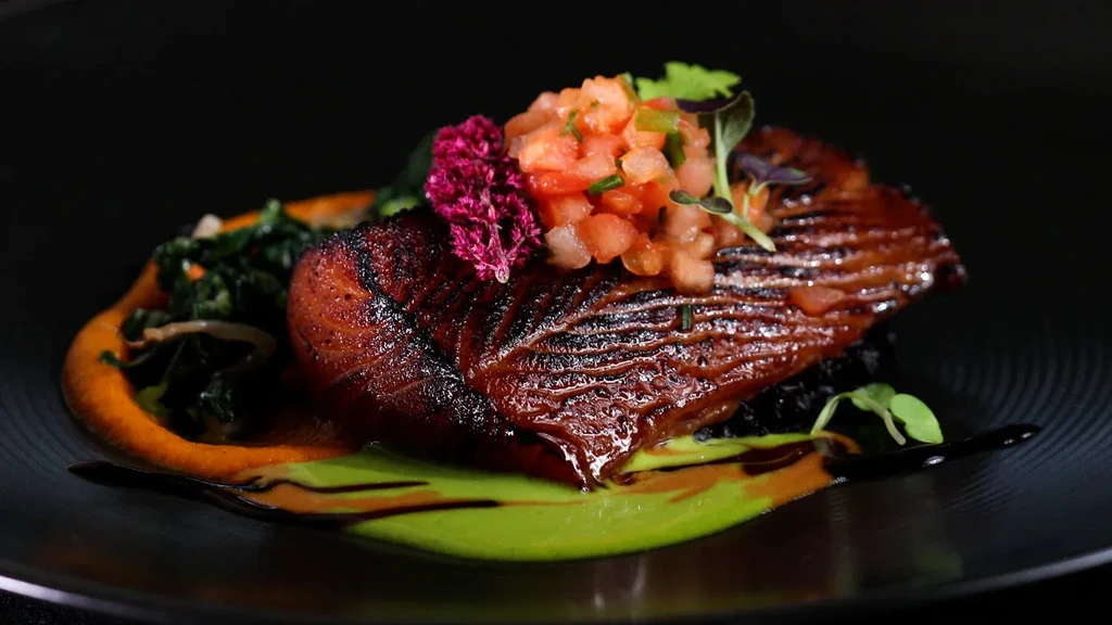 Elegantly plated grilled protein with salsa, dark rice, and sauces.