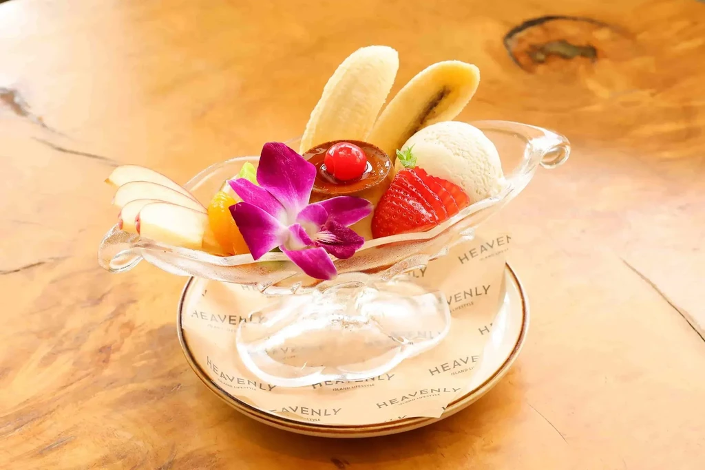 Banana split sundae with ice cream, flan, strawberries, and orchid.