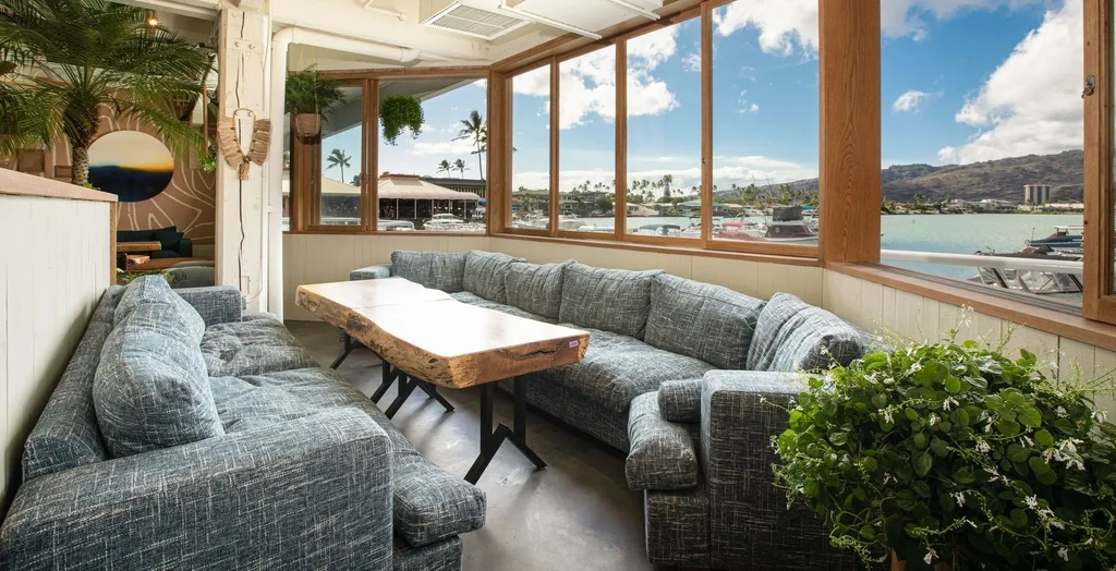 Coastal restaurant lounge with tropical seating area overlooking a marina.