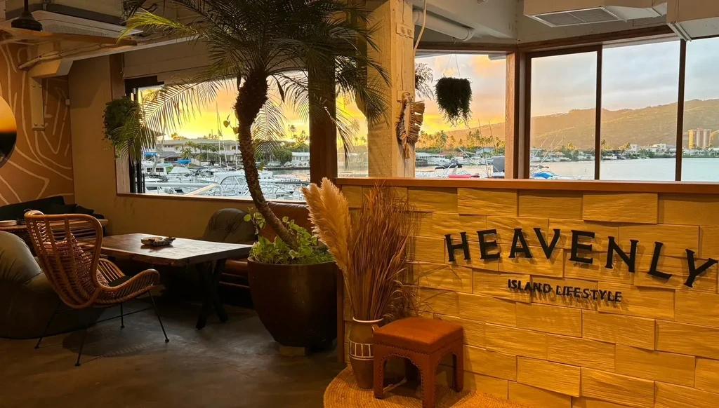 Tropical cafe interior with "Heavenly Island Lifestyle" sign and marina view.