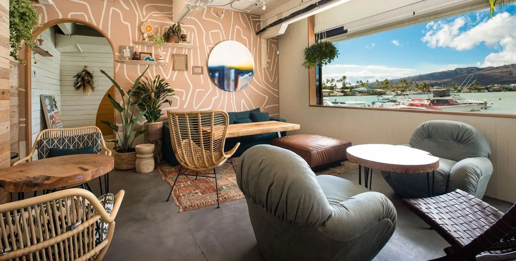 Modern tropical cafe interior with varied seating and waterfront view.