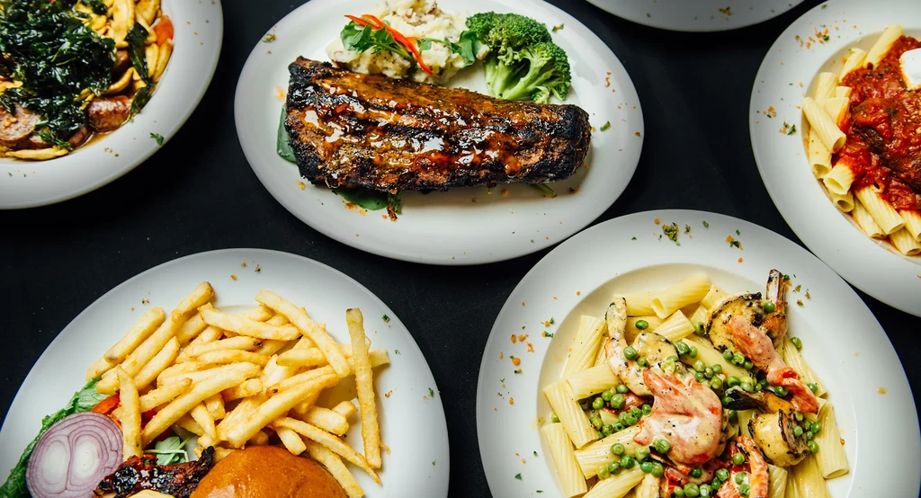 Top-down view of five distinct dishes: pasta, meat, burger, shrimp.