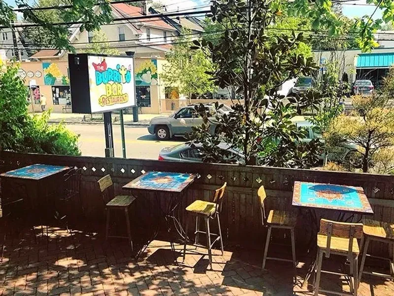 Outdoor patio of a restaurant next to a street with cars.