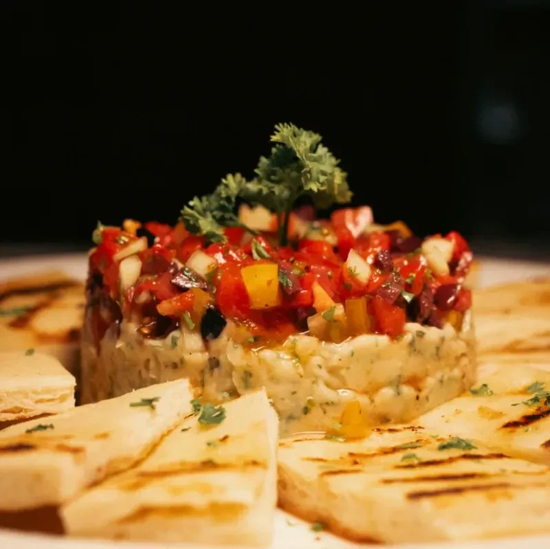 Hummus topped with salsa, garnished with parsley and served with pita bread.