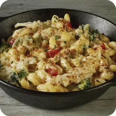 Cheesy chicken, broccoli, tomato pasta bake in a cast-iron skillet.