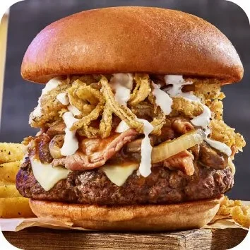 Gourmet burger with beef patty, cheese, bacon, mushrooms, and fried onions.