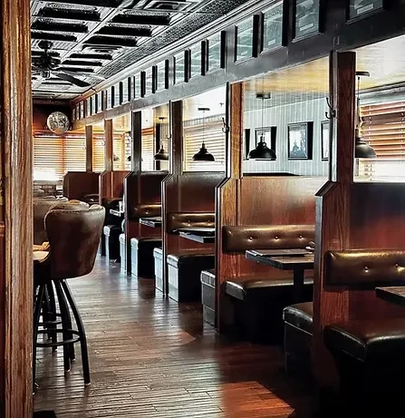 Long aisle of dark wood booths and a barstool in a restaurant.