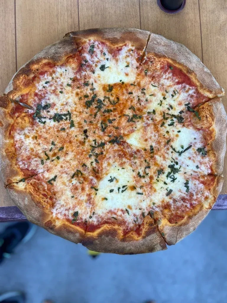 A Margherita pizza with basil on a wooden table, top view.