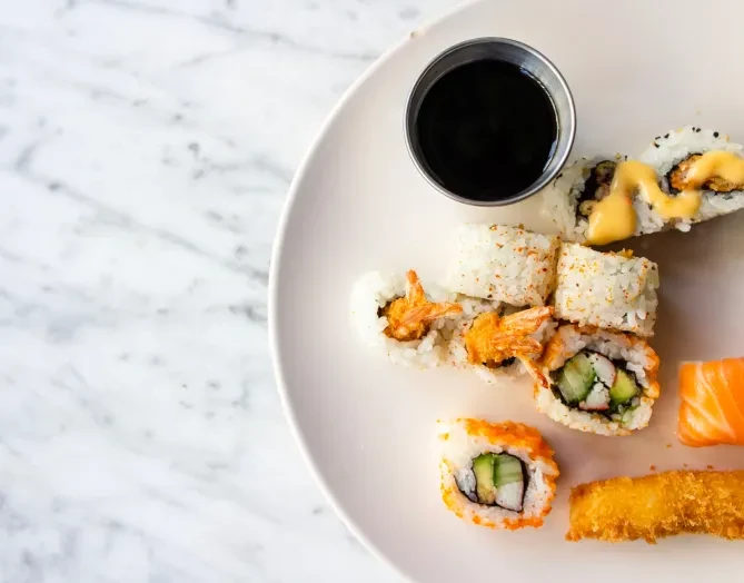 Overhead view of a white plate with various sushi rolls.