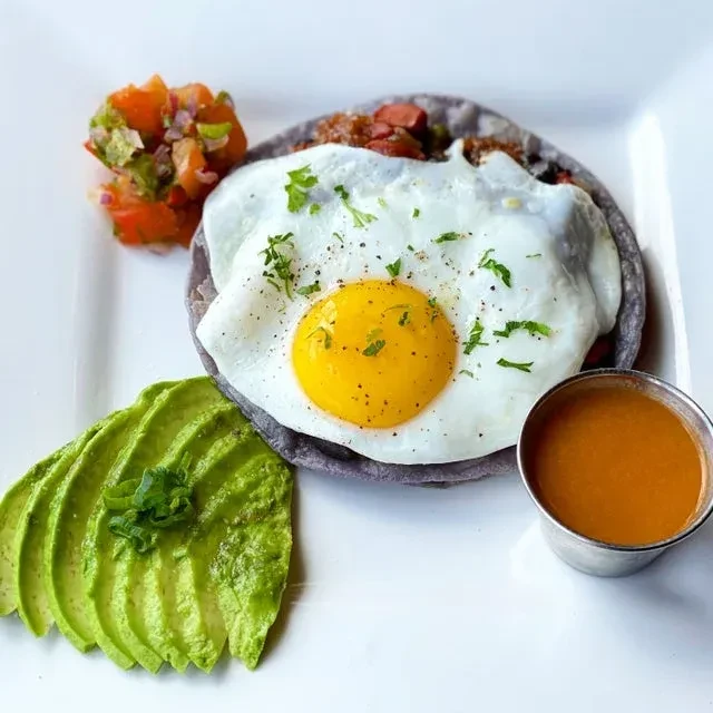 Huevos rancheros with a sunny-side-up egg, avocado, and salsa.