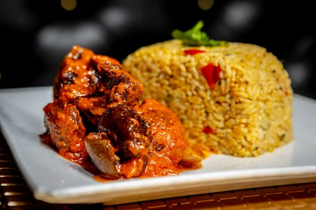 Spicy meat and yellow rice on a white rectangular plate.