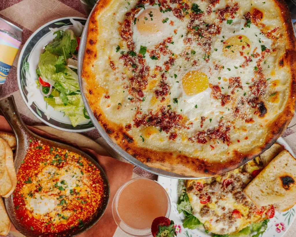 A top-down view of breakfast foods including pizza, shakshuka, and an omelet.
