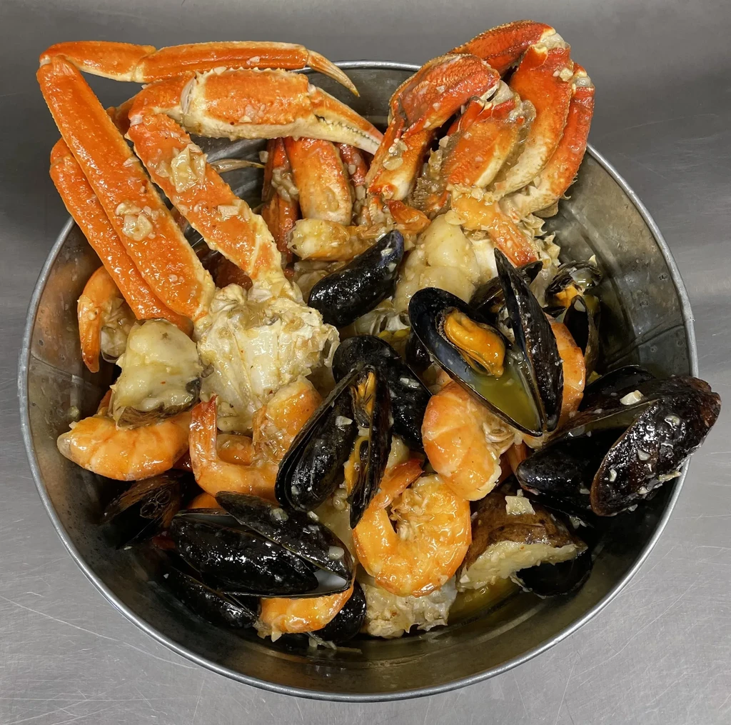 A metal bucket filled with crab legs, mussels, and shrimp.