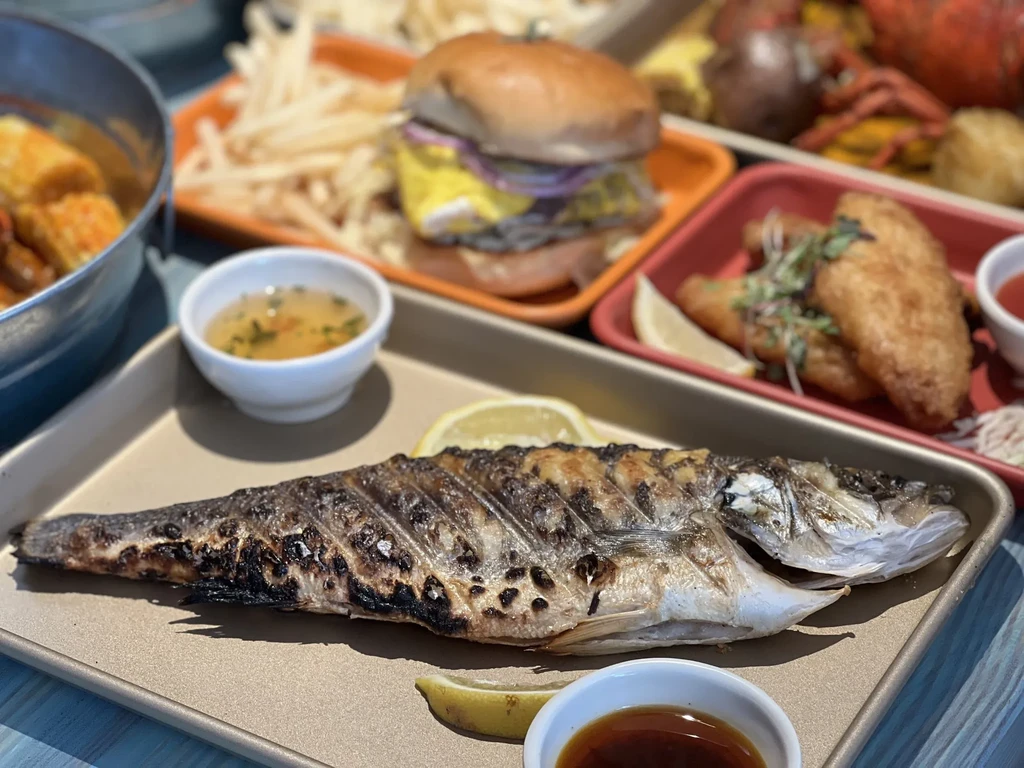 A grilled whole fish with lemon, sauces, and other dishes.