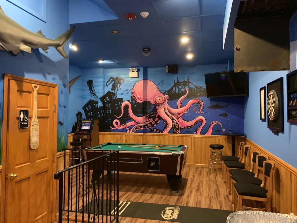 A game room with an underwater mural, pool table, and dartboard.