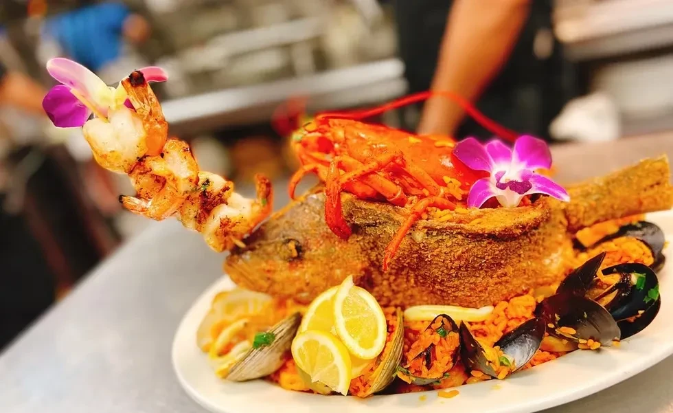 Whole fried fish, lobster, shrimp, mussels, clams, and rice on a plate.