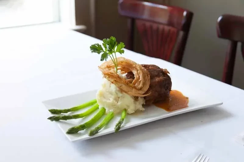Plated meal with meat, mashed potatoes, onion rings, and asparagus.