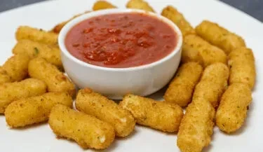 Golden-brown fried mozzarella sticks surround a bowl of marinara sauce.