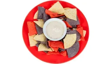 Red plate with multi-colored tortilla chips and a creamy dip.