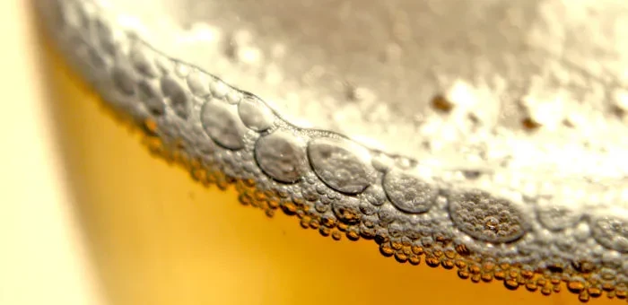 Close-up of effervescent bubbles in amber foam clinging to glass.