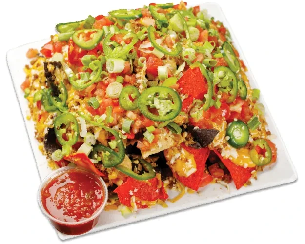 Plate of colorful nachos with cheese, meat, vegetables, and salsa.