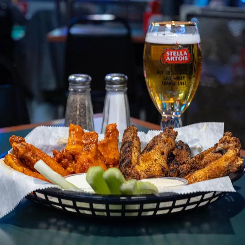 Basket of buffalo and grilled chicken wings with Stella Artois beer.