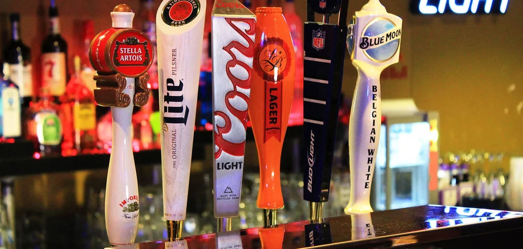 Close-up of branded beer tap handles lined up at a bar.