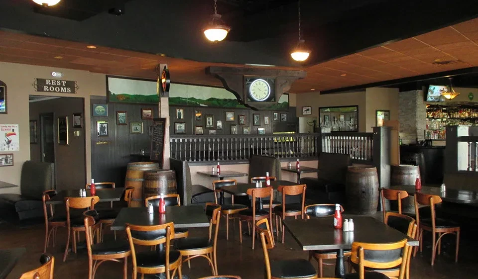 Cozy, traditional pub interior with unoccupied dining area and well-stocked bar.