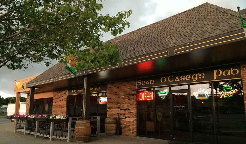 Sean O'Casey's Irish Pub exterior with patio, flags, and neon signs.