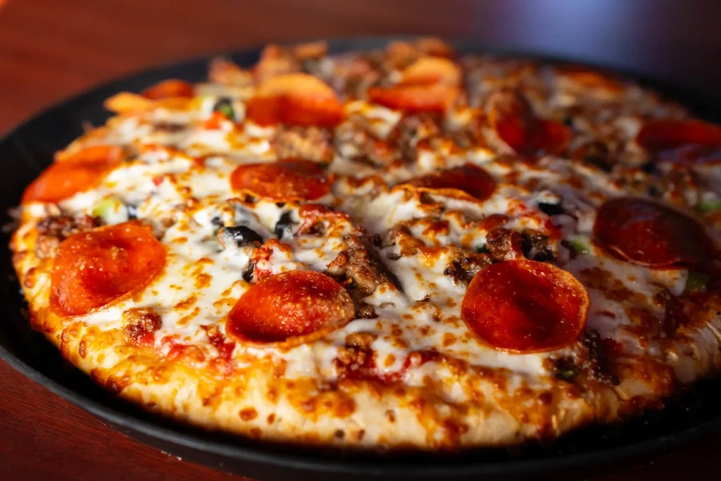 Freshly baked half-and-half pizza with pepperoni, meat, olives, and peppers.