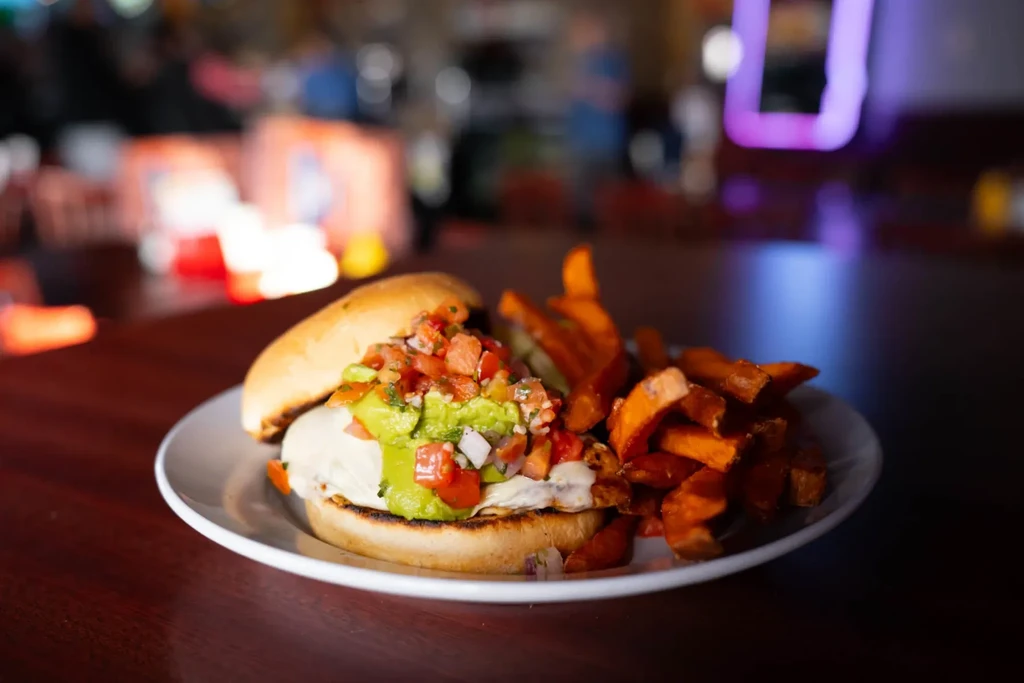 Gourmet sandwich with creamy sauce, guacamole, pico de gallo, sweet potato fries.