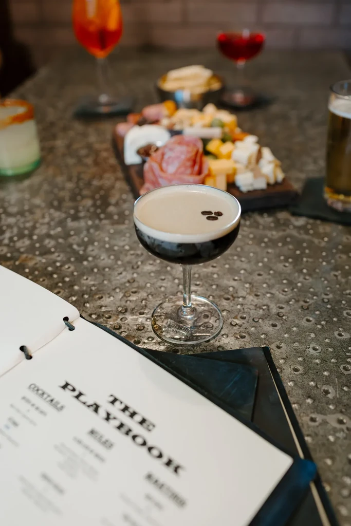 Creamy espresso martini with coffee beans and a large charcuterie board.