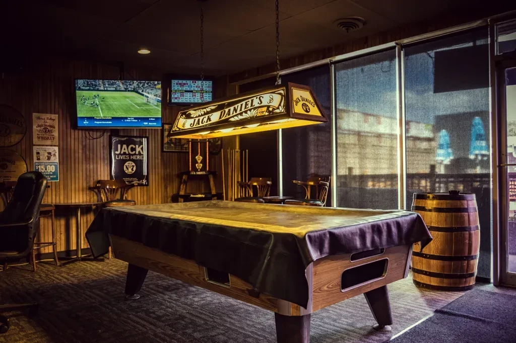 Bar interior with covered pool table and Jack Daniel's light fixture.