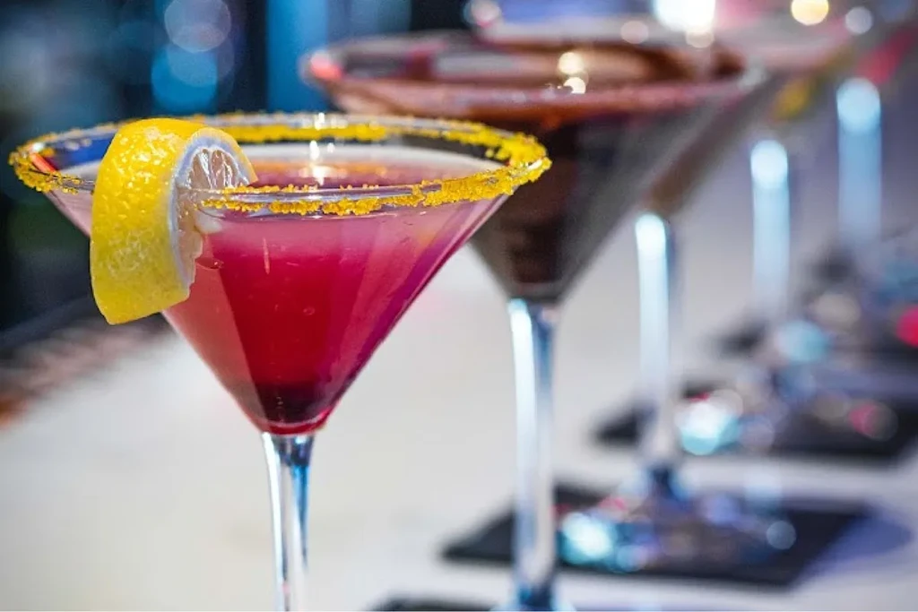 Magenta martini, lemon-sugar rim, sharp focus, blurred cocktails.