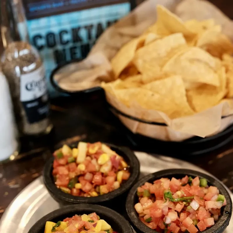 Three salsas, chips, and a Corona beer at a restaurant.