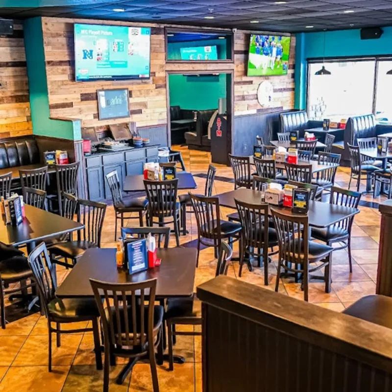 Empty casual restaurant with distressed wood and teal walls, flat-screen TVs.