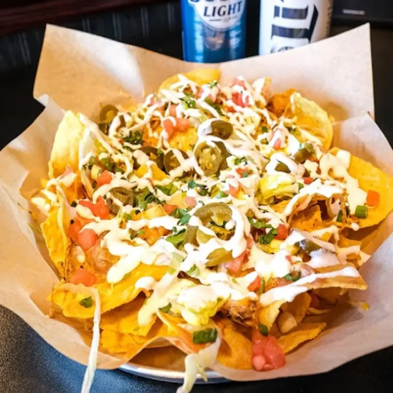 Large loaded nachos with cheese, jalapeños, tomatoes, herbs, and a Bud Light.