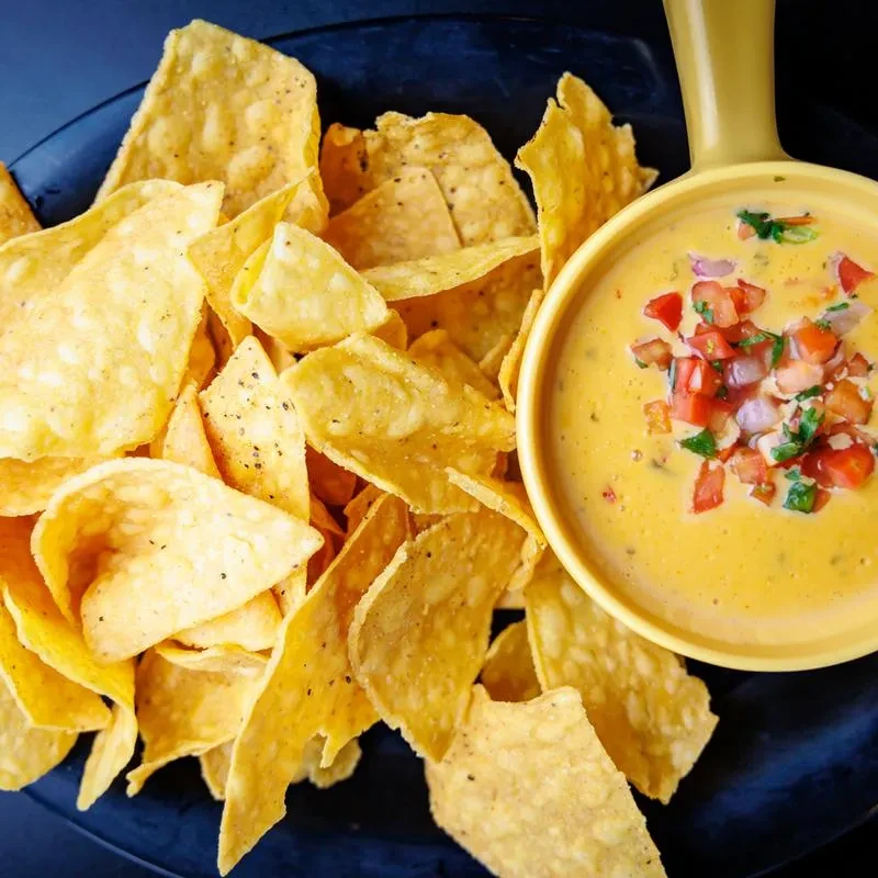 Golden tortilla chips and queso topped with pico de gallo.