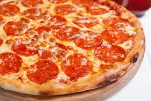 Freshly baked pepperoni pizza with melted cheese on wooden peel.
