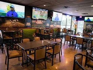 Casual sports bar interior with dining tables and TVs showing baseball.
