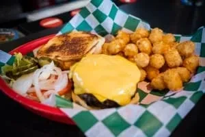 Cheeseburger, tater tots, and toppings served in a red diner basket.