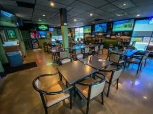 Casual sports bar dining area with multiple TVs and green walls.